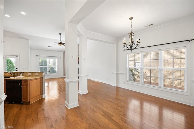 unfurnished dining area with visible vents, decorative columns, ceiling fan with notable chandelier, and wood finished floors