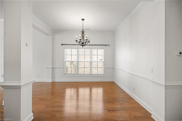 unfurnished dining area with an inviting chandelier, crown molding, and wood finished floors