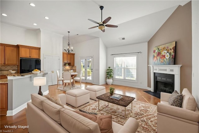 living area with wood finished floors, high vaulted ceiling, recessed lighting, a fireplace with flush hearth, and ceiling fan with notable chandelier