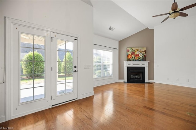 unfurnished living room with visible vents, lofted ceiling, wood finished floors, ceiling fan, and a fireplace with flush hearth