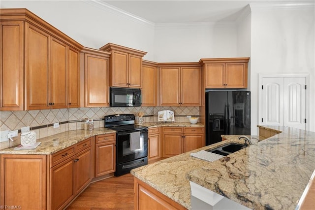 kitchen with crown molding, light wood finished floors, brown cabinets, and black appliances