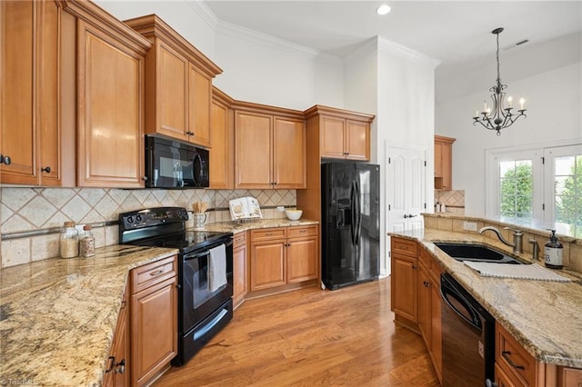 kitchen featuring visible vents, ornamental molding, light wood finished floors, black appliances, and decorative light fixtures