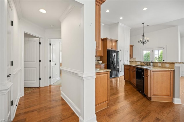 kitchen with brown cabinets, a notable chandelier, a sink, light wood finished floors, and black appliances