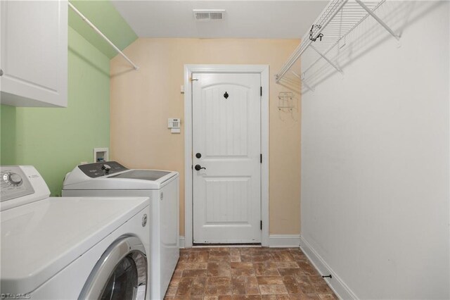 washroom with washer and dryer, cabinet space, stone finish floor, baseboards, and visible vents
