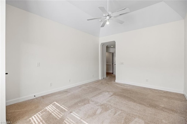 empty room with baseboards, ceiling fan, vaulted ceiling, and light carpet