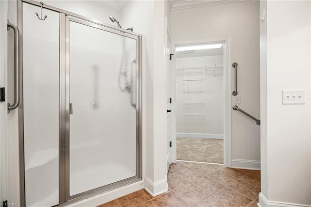 bathroom featuring tile patterned floors, ornamental molding, baseboards, and a shower stall