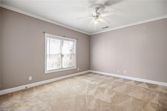 spare room featuring ceiling fan, visible vents, baseboards, ornamental molding, and light carpet