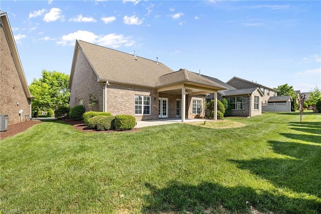 rear view of house with a patio, a yard, and brick siding