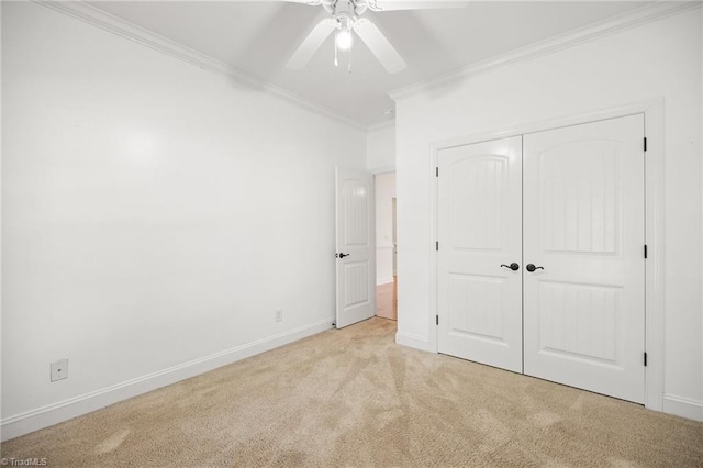 unfurnished bedroom with crown molding, a closet, baseboards, light colored carpet, and a ceiling fan
