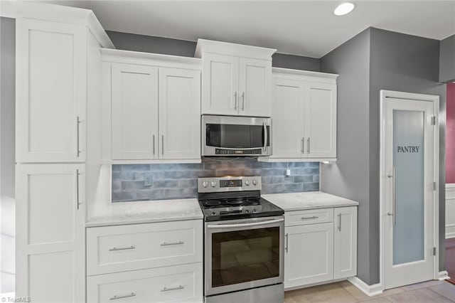 kitchen with white cabinets, appliances with stainless steel finishes, and backsplash