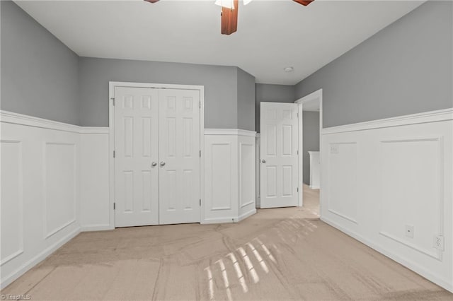 unfurnished bedroom with ceiling fan, a closet, and light colored carpet