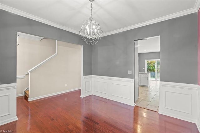 empty room with hardwood / wood-style flooring, crown molding, and a chandelier