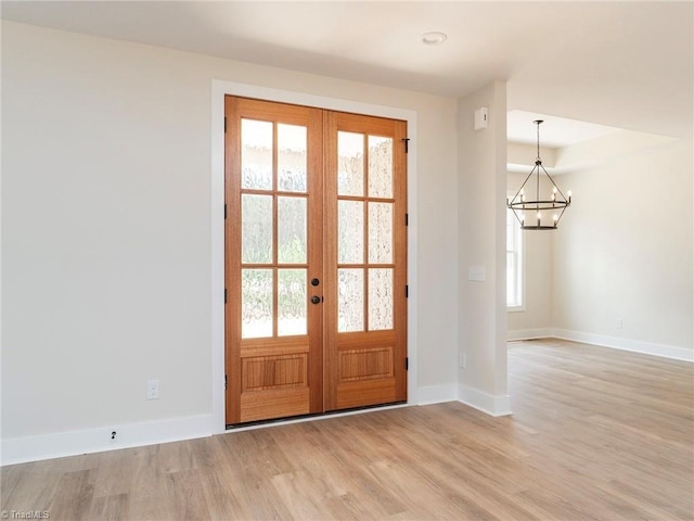 entryway featuring a notable chandelier, light wood-type flooring, and french doors