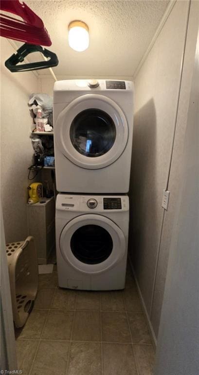 clothes washing area featuring stacked washer / dryer and a textured ceiling