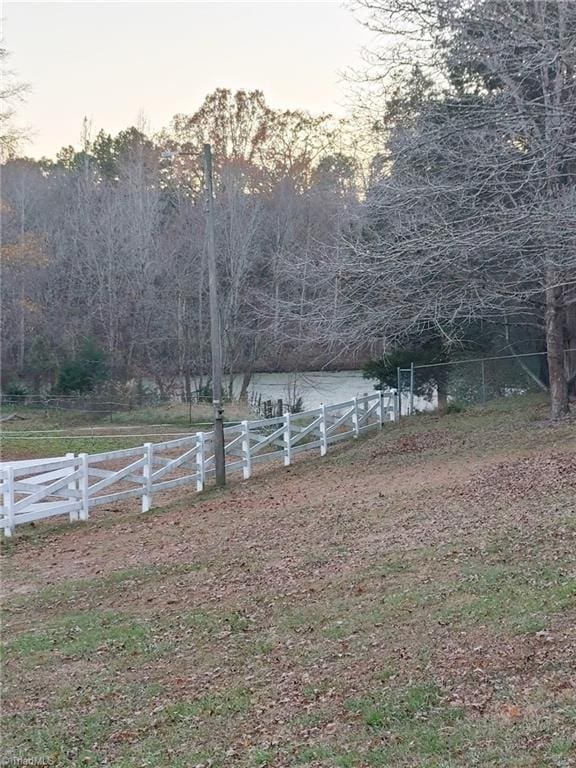 yard at dusk featuring a rural view