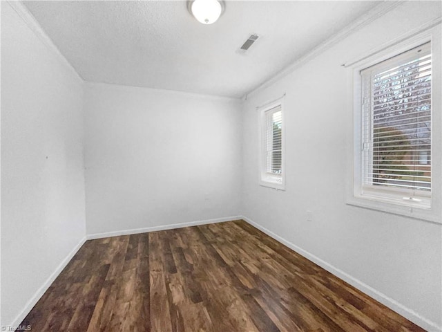 spare room with dark wood finished floors, visible vents, and baseboards