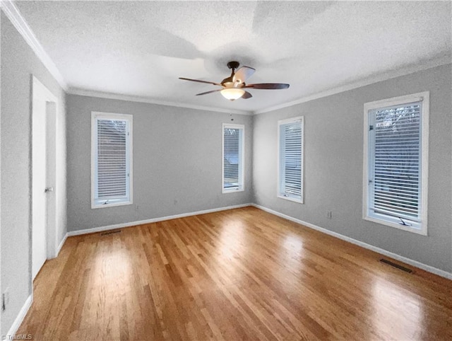 empty room featuring light wood-style floors, visible vents, and ornamental molding