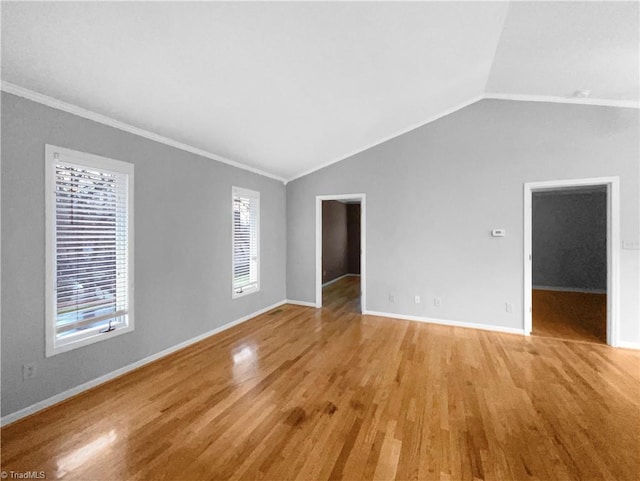 spare room featuring light wood-style flooring, crown molding, lofted ceiling, and a healthy amount of sunlight