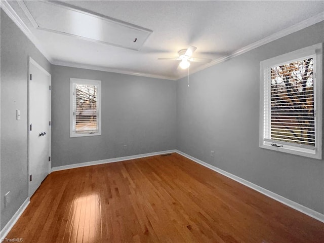 empty room with a ceiling fan, crown molding, wood finished floors, and baseboards