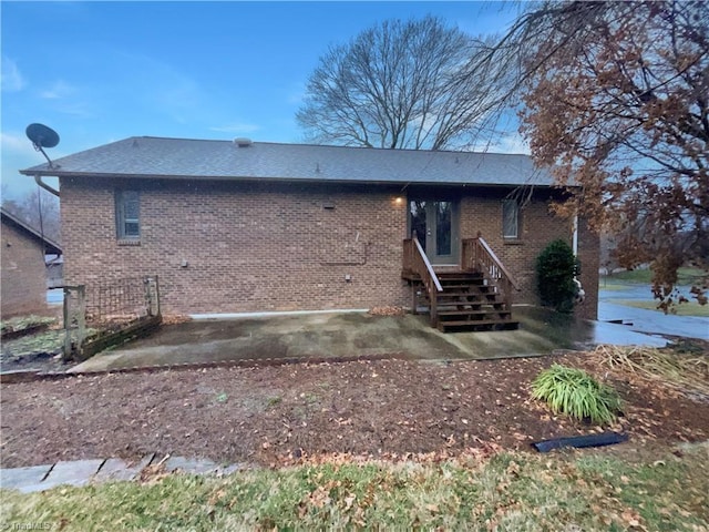 exterior space featuring brick siding, roof with shingles, and entry steps