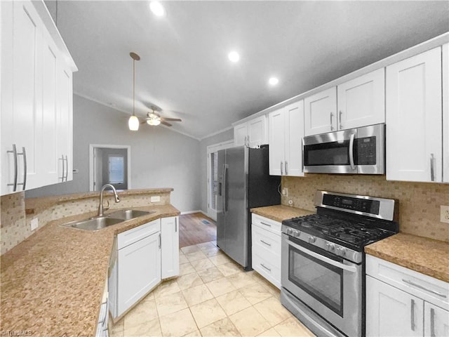 kitchen with a sink, stainless steel appliances, white cabinets, and vaulted ceiling