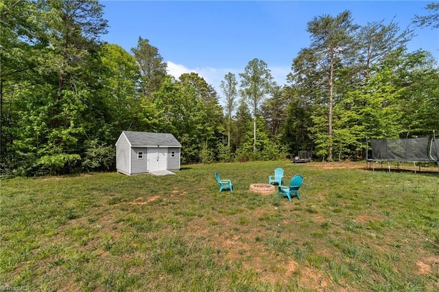 203 Cross Country Chase, Stokesdale, NC 27357 - view of yard featuring a trampoline, a storage shed, an outbuilding, a fire pit, and a wooded view