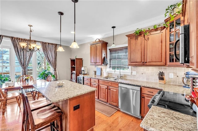 kitchen with sink, a center island, stainless steel appliances, pendant lighting, and a chandelier