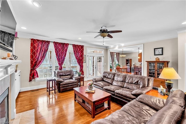 living room with a tile fireplace, ceiling fan, and ornamental molding