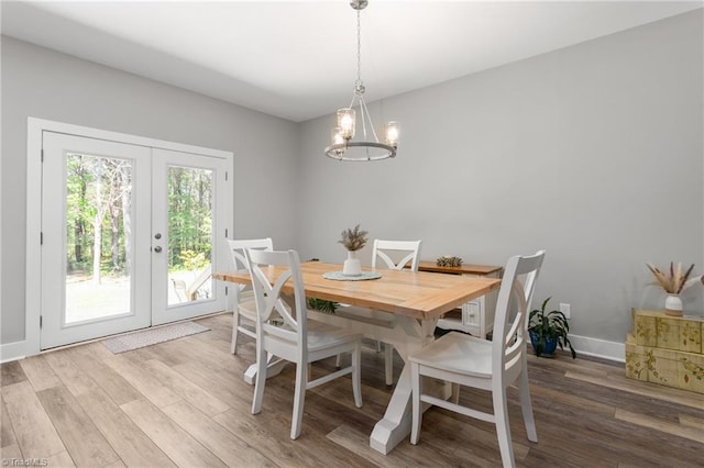 dining space with baseboards, a chandelier, french doors, and wood finished floors