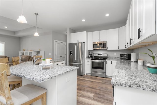 kitchen featuring a kitchen breakfast bar, stainless steel appliances, light wood-type flooring, and white cabinetry