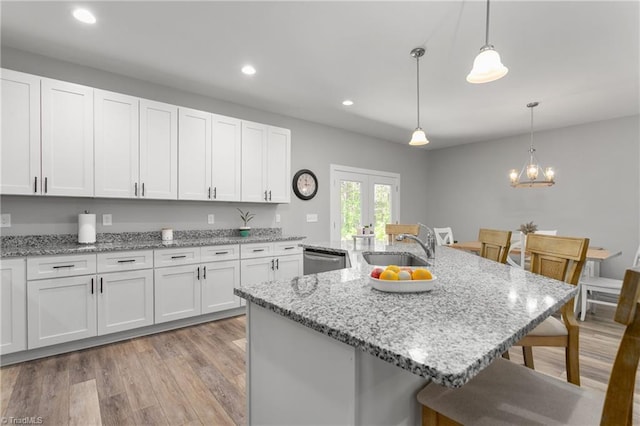 kitchen featuring white cabinets, a sink, dishwasher, a breakfast bar area, and french doors