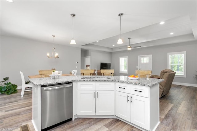 kitchen featuring stainless steel dishwasher, a sink, a tray ceiling, and open floor plan