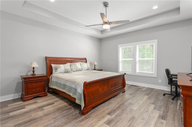 bedroom with baseboards, ceiling fan, light wood-type flooring, recessed lighting, and a tray ceiling