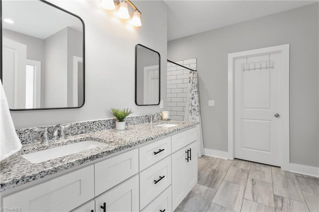 bathroom with double vanity, baseboards, and a sink