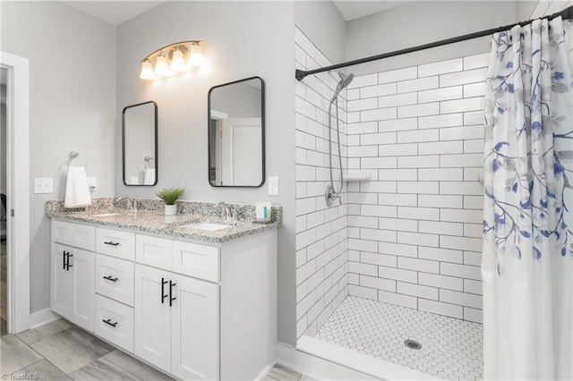 bathroom featuring a sink, double vanity, and tiled shower