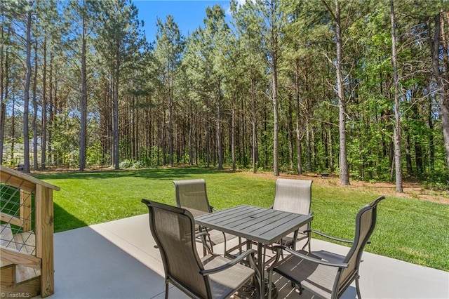 view of patio with outdoor dining area and a wooded view