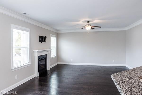 unfurnished living room with ornamental molding, a healthy amount of sunlight, ceiling fan, and dark hardwood / wood-style floors