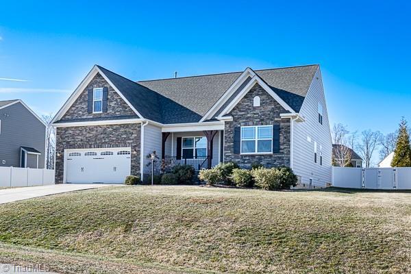 view of front of property featuring a garage, a front lawn, and a porch