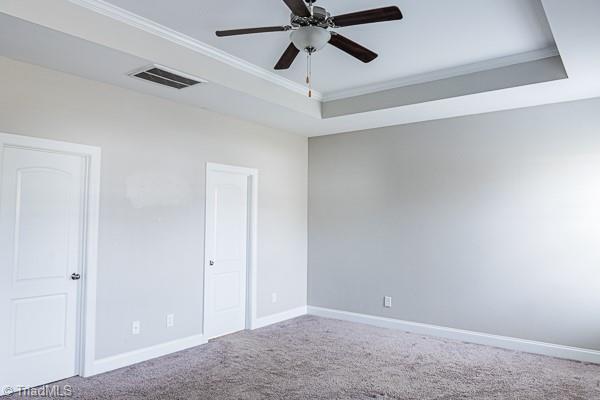 unfurnished room with ornamental molding, carpet flooring, ceiling fan, and a tray ceiling