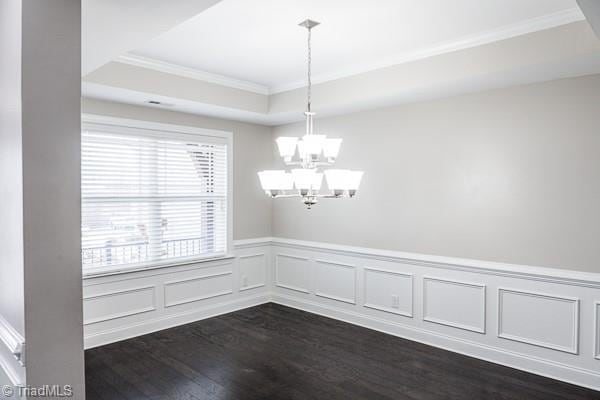 interior space with dark hardwood / wood-style floors, ornamental molding, a tray ceiling, and a notable chandelier