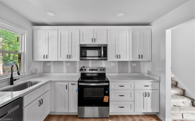 1710 Scarborough Rd, High Point, NC 27265 - kitchen with appliances with stainless steel finishes, white cabinets, light wood-style flooring, light stone counters, and recessed lighting
