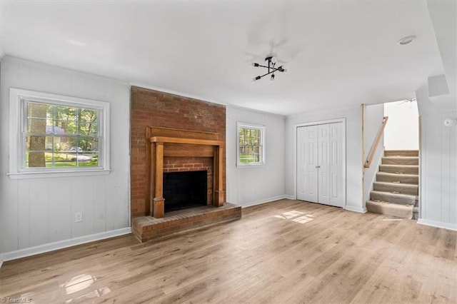 1710 Scarborough Rd, High Point, NC 27265 - unfurnished living room featuring wood finished floors, stairway, and a brick fireplace