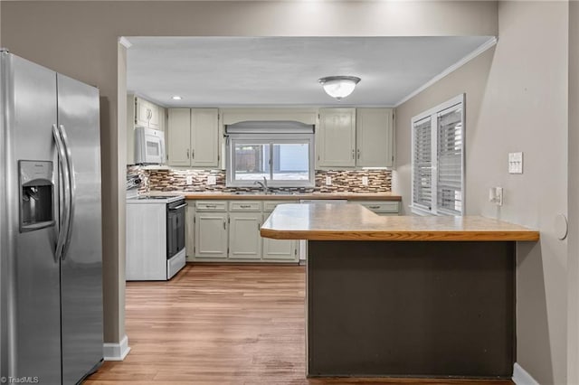 kitchen with light countertops, crown molding, a peninsula, white appliances, and a sink