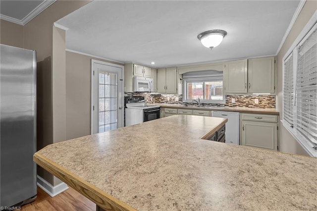 kitchen with white appliances, backsplash, crown molding, and a sink