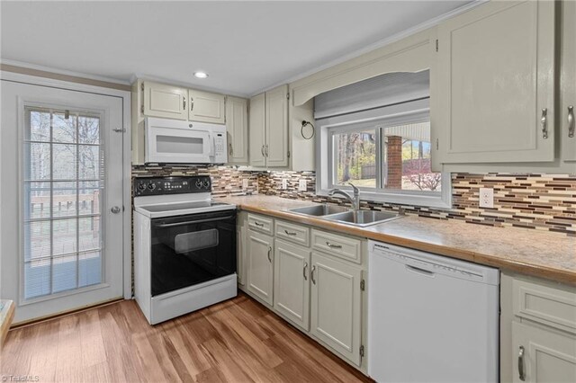 kitchen featuring light countertops, white appliances, tasteful backsplash, a sink, and light wood-type flooring