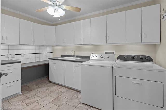 laundry room with washing machine and clothes dryer, crown molding, a ceiling fan, a sink, and cabinet space