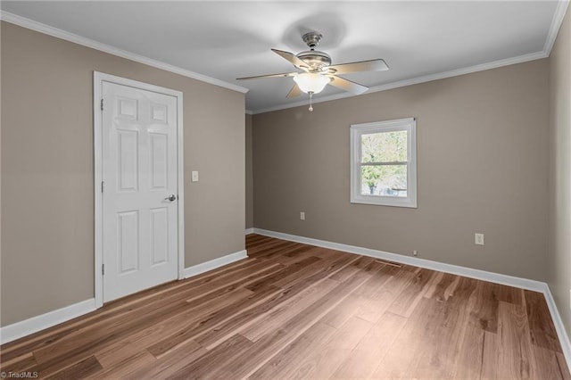 spare room featuring ornamental molding, baseboards, ceiling fan, and wood finished floors