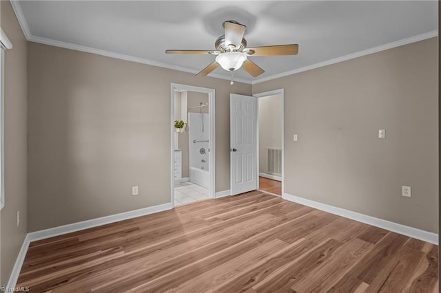 unfurnished bedroom with baseboards, ensuite bath, wood finished floors, and ornamental molding