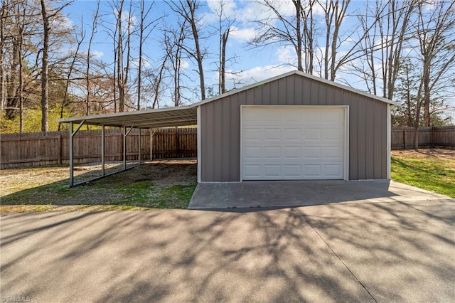 garage featuring driveway, a garage, and fence