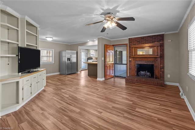 unfurnished living room with light wood-type flooring, ceiling fan, ornamental molding, and a brick fireplace